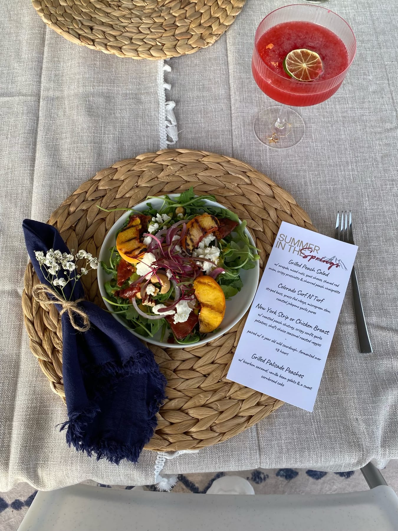 A place setting with a printed menu card, a salad and a cocktail